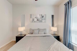 A bedroom with a bed, two bedside tables, a mirror, and a window with curtains. - Spacious South Temple Home with 5 Bed (Temple)
