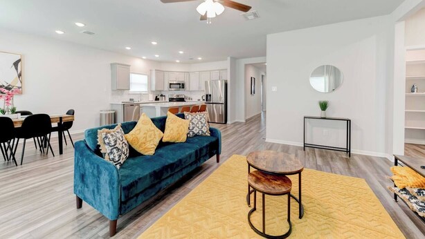 A modern living room with a blue sofa, a wooden coffee table, and a yellow rug.