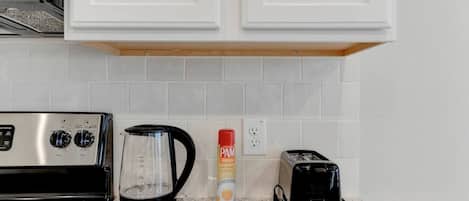 Una cocina equipada con estufa, cafetera y tostadora.