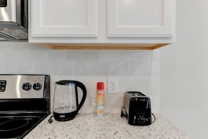 A kitchen with a stove, coffee maker, and toaster.