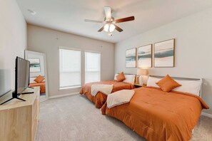 A bedroom with two beds, a ceiling fan, a TV, and artwork on the wall. - Spacious 4 Bedroom Home In Troy (Troy)