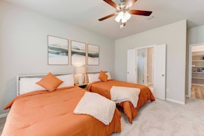 A hotel room with two beds, a ceiling fan, artwork on the wall, and a walk-in closet.