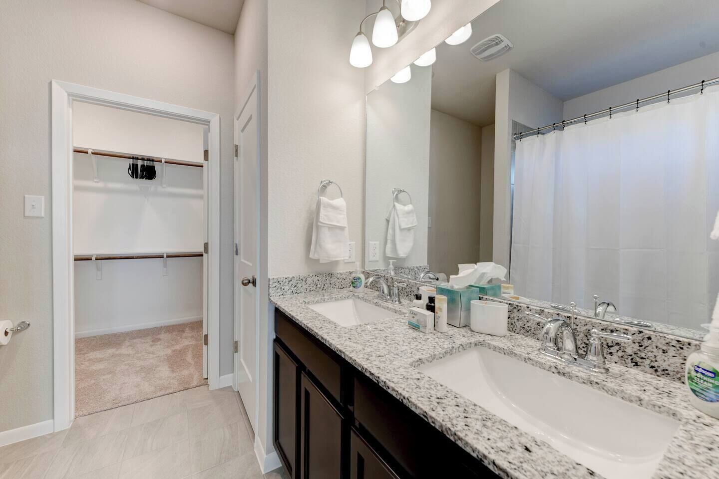 A bathroom with two sinks, a large mirror, and a shower curtain.
