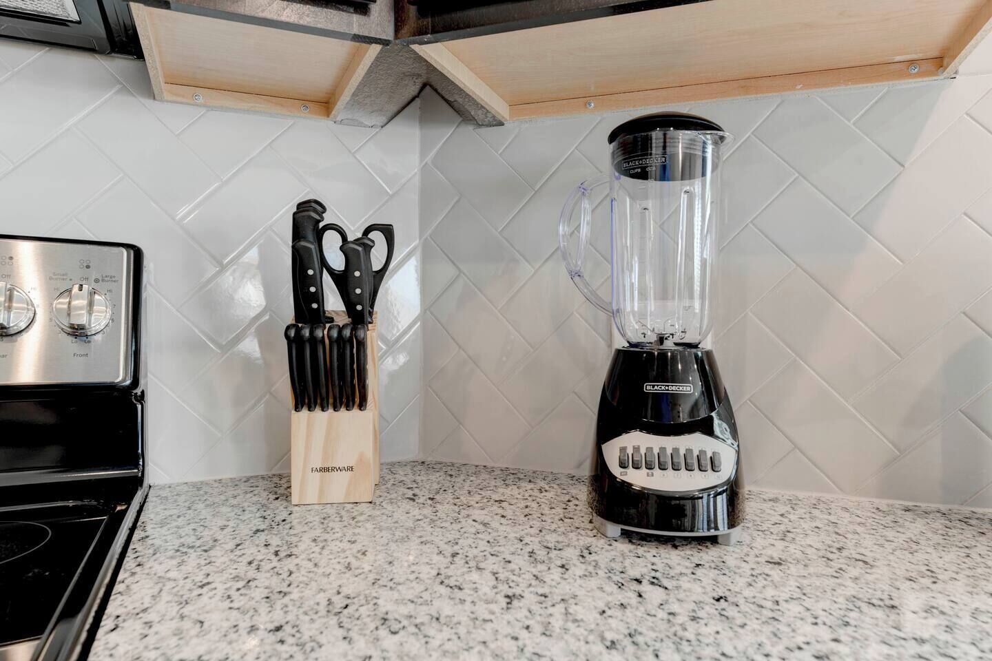 A kitchen with a stove, a knife block, and a blender.