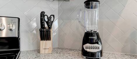 A kitchen with a stove, a knife block, and a blender.