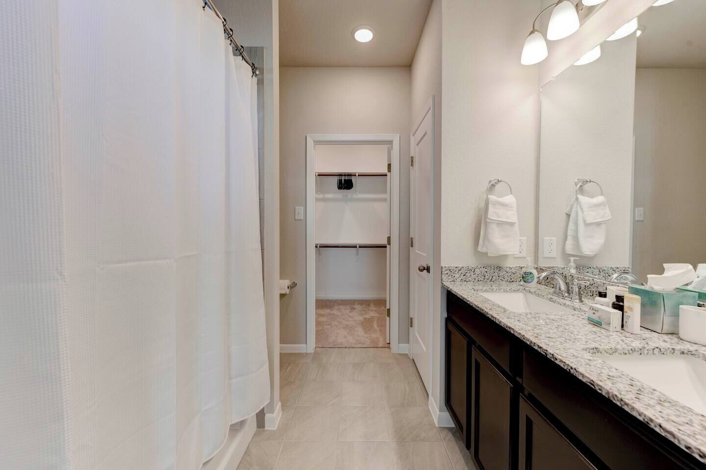 Un baño con ducha, lavabo y espejo, y un perchero para toallas.