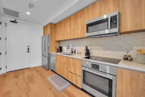 Una cocina moderna con electrodomésticos de acero inoxidable, armarios de madera y encimera de granito.
