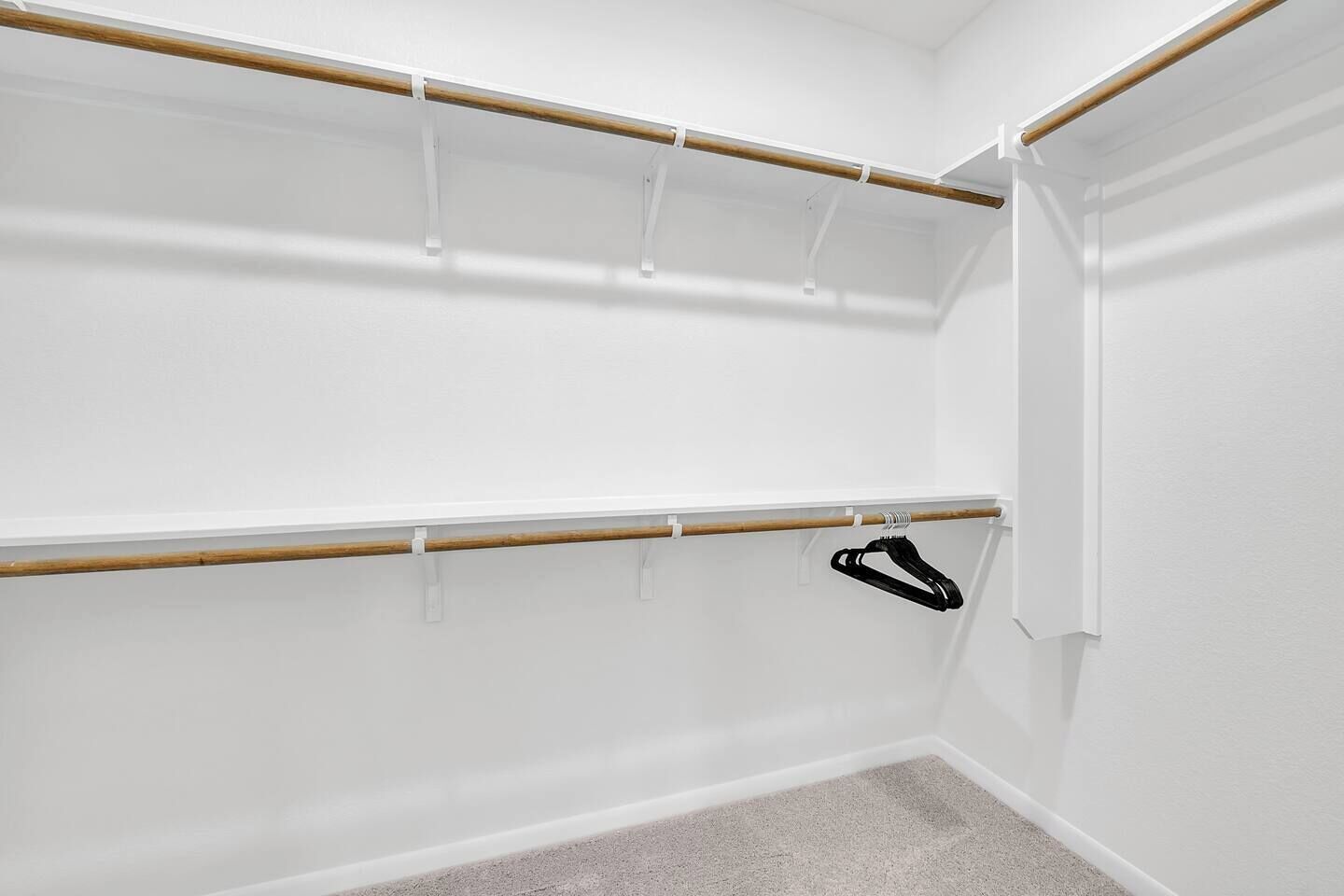 A closet with wooden rods and a black hanger.
