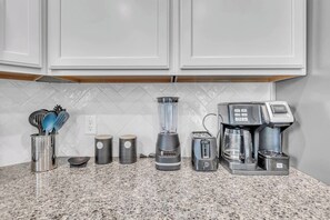 Eine Küchenarbeitsplatte mit Mixer, Toaster, Kaffeemaschine und einer Utensilienhalterung.