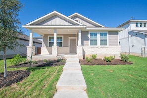 A two-story house with a front porch, a stone foundation, and a well-maintained lawn.