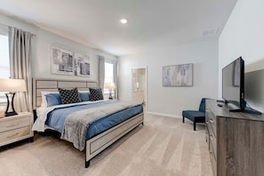 A modern bedroom with a bed, bedside tables, a TV, and artwork on the walls.