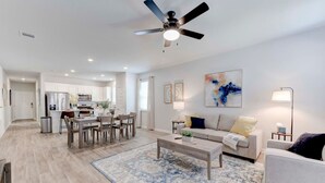 A modern living room with a sofa, coffee table, and a dining area with chairs and a table.