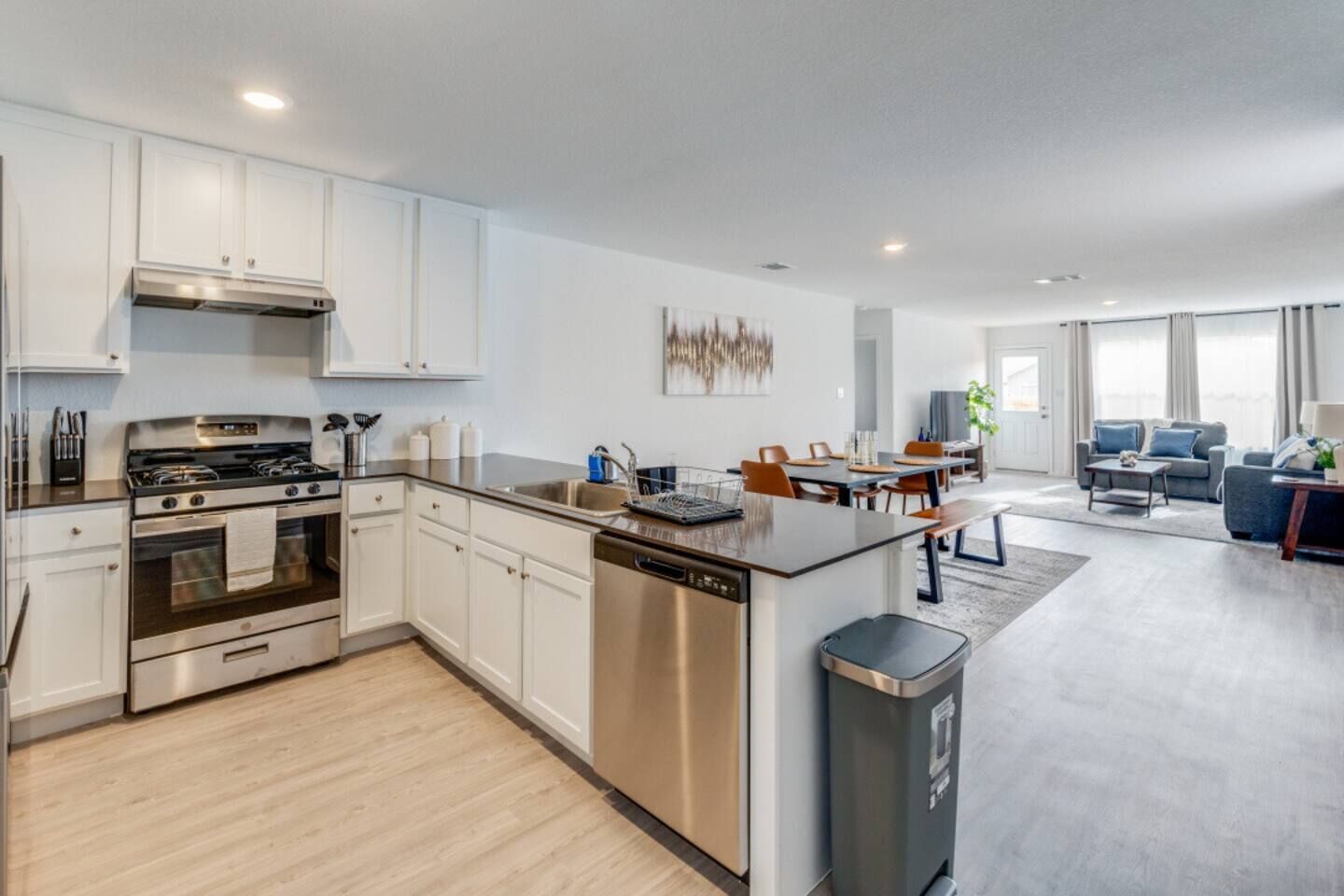 A modern kitchen with stainless steel appliances, a dishwasher, and a dining area with a table and chairs.