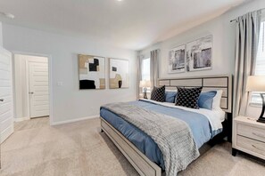 A bedroom with a bed, bedside tables, and artwork on the walls. - Round Rock Executive Suite (Round Rock)