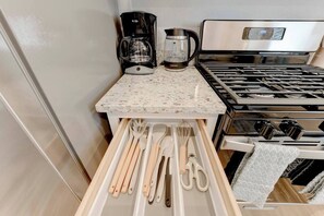 A kitchen with a stove, coffee maker, and utensils drawer. - Round Rock Executive Suite (Round Rock)