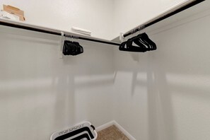 A corner of a room with a white wall, a white door, and a white floor. There is a black hanger rack with several black hangers. - Round Rock Executive Suite (Round Rock)