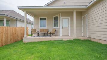 A residential house with a covered patio, a wooden fence, and a well-maintained lawn.