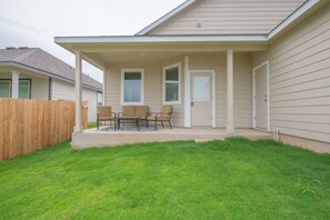 A residential house with a covered patio, a wooden fence, and a well-maintained lawn. - Hutto Executive Space (Hutto)