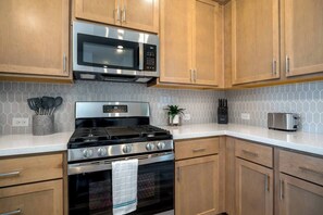 A kitchen with wooden cabinets, a stainless steel microwave, a gas stove, and a toaster.