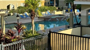 A pool area with lounge chairs, palm trees, and a clear view of the surrounding buildings.