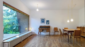 A dining area with a wooden table and chairs, a radiator under a window, and two wall-mounted light fixtures.
