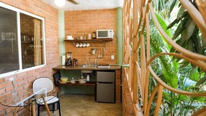 A compact kitchen with a brick wall, a microwave, and a sink. - Casa Redonda 🌼 Casita 1 🌞SayulitaWifi 💛 Central (Sayulita)