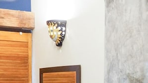 A room with a wooden headboard bed, a decorative wall shield, and a partial view of a window. - Casa Redonda 🌼 Casita 1 🌞SayulitaWifi 💛 Central (Sayulita)