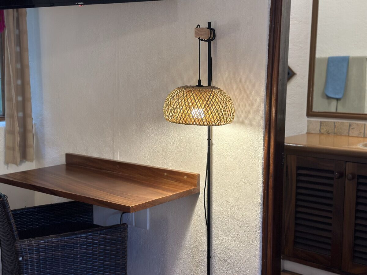 Una habitación con una mesa de madera, una silla de mimbre y una lámpara colgante.
