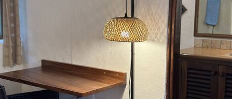 Una habitación con una mesa de madera, una silla de mimbre y una lámpara colgante.
