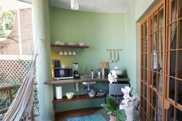 A compact kitchen with a microwave, sink, and various utensils.