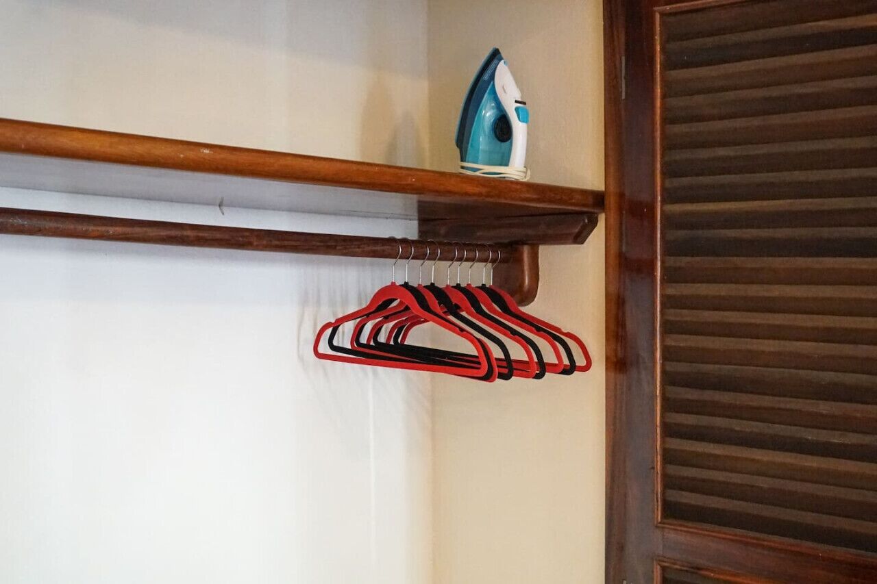 Un estante de madera con un perchero y un planchado.