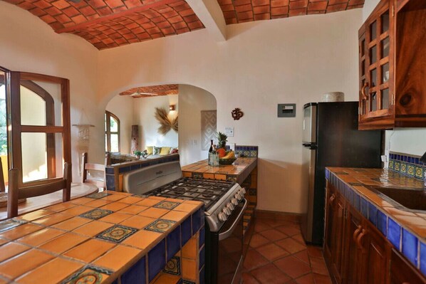 A kitchen with a gas stove, tiled backsplash, and wooden cabinets.