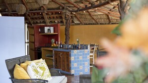 An outdoor seating area with wicker furniture, a tiled bar counter, and a thatched roof structure.