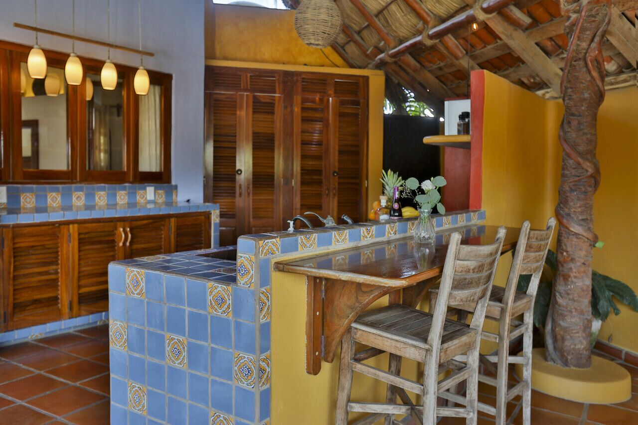 A kitchen with a tiled backsplash, wooden cabinets, and a bar area with chairs.