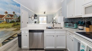A modern kitchen with white cabinetry, a dishwasher, a microwave, and a toaster.