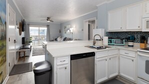 A modern kitchen with white cabinetry, a dishwasher, a microwave, and a toaster.