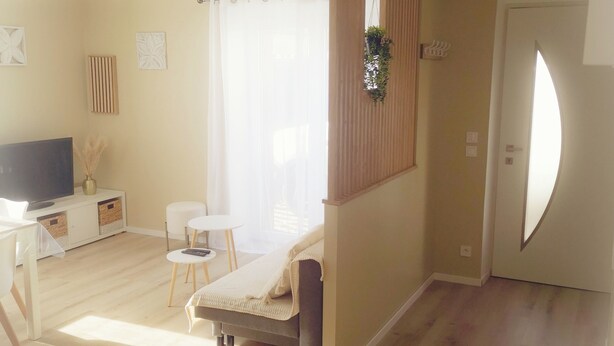 Een moderne woonkamer met een bank, een televisie en een eethoek met een tafel en stoelen.