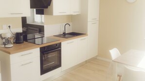 Een moderne keuken met witte kasten, een zwart fornuis en een houten aanrecht.