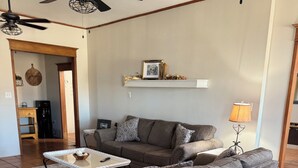 A living room with a grey sofa, a white coffee table, a floor lamp, and a ceiling fan.