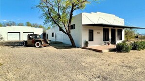 A two-story building with a white exterior, a driveway, and a parked vintage car.