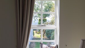 A bedroom with a window, a bed, a bedside table, and a lamp. - Hill House Lodge, overlooking the Rock of Cashel (Cashel)