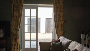 A living room with a sofa, a television, and a door leading outside. - Hill House Lodge, overlooking the Rock of Cashel (Cashel)