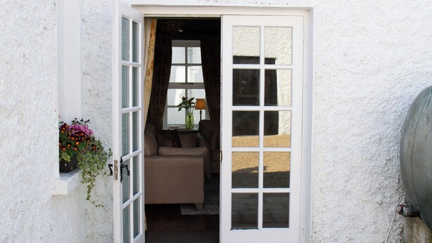 A white exterior wall with a door leading to a room with a sofa and a lamp. - Hill House Lodge, overlooking the Rock of Cashel (Cashel)
