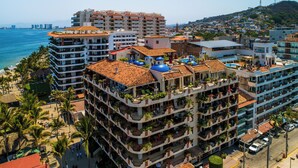 A multi-story hotel with balconies, a rooftop pool, and a view of the beach and ocean. - SUMMER PROMO: 6th Floor Corner Unit on the beach in Old Town; Rooftop Pool (Puerto Vallarta)