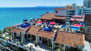 A hotel with multiple blue-domed structures, a swimming pool, and a view of the sea. - SUMMER PROMO: 6th Floor Corner Unit on the beach in Old Town; Rooftop Pool (Puerto Vallarta)