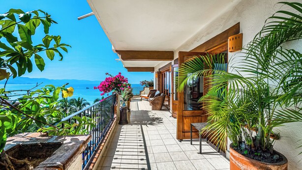 A balcony with a view of the sea, potted plants, and wicker furniture. - SUMMER PROMO: 6th Floor Corner Unit on the beach in Old Town; Rooftop Pool (Puerto Vallarta)