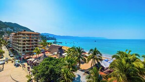 A coastal hotel with multiple floors, a beach area with umbrellas, and a view of the sea. - SUMMER PROMO: 6th Floor Corner Unit on the beach in Old Town; Rooftop Pool (Puerto Vallarta)
