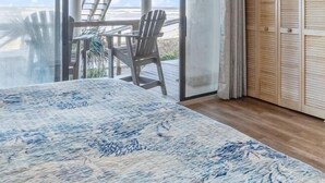 A bedroom with a large sliding glass door leading to an outdoor deck with a table and chairs, a wooden ceiling, and a wardrobe with louvered doors. - NEW LISTING - Oceanfront Condo ~ Excellent Location (Saint Augustine)