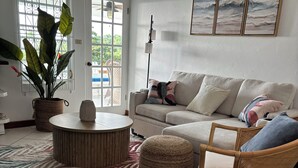 A living room with a sofa, a round coffee table, a wicker chair, a large potted plant, and a zebra-patterned rug. - Paradise View - Stunning views near Dickenson Bay Beach in Antigua & Barbuda (Dickenson Bay Beach)