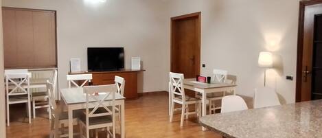 A compact living space with a dining area, a TV, and a kitchen counter.
